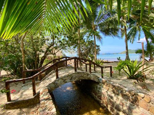 a stone bridge over a river in front of the ocean at Ocamocam Beach Martins in New Busuanga