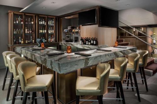 a bar in a restaurant with a marble counter and chairs at Hyatt Centric Arlington in Arlington