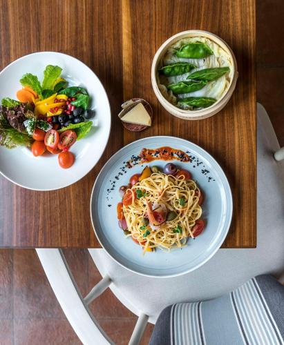 a table with two plates of pasta and a bowl of vegetables at Hyatt Centric MG Road Bangalore in Bengaluru