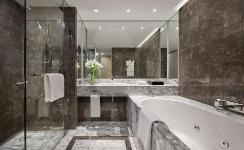 a bathroom with a tub and a sink and a mirror at Grand Hyatt Melbourne in Melbourne