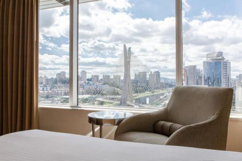 a bedroom with a chair in front of a large window at Grand Hyatt São Paulo in Sao Paulo
