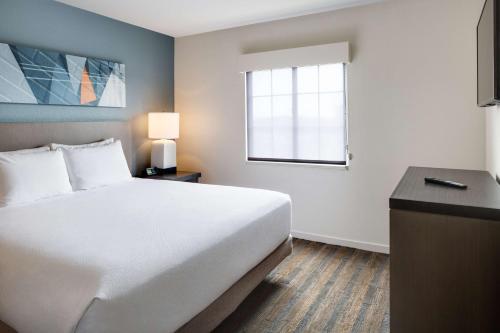 a hotel room with a bed and a window at Hyatt House Boston Waltham in Waltham