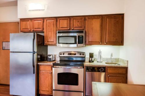 a kitchen with wooden cabinets and stainless steel appliances at Hyatt House Chicago Schaumburg in Schaumburg
