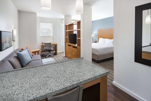 a hotel room with a bed and a living room at Hyatt House Boulder/Broomfield in Broomfield