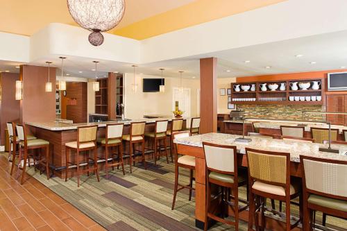 un restaurant avec un grand bar doté de tables et de chaises en bois dans l'établissement Hyatt House Dallas Las Colinas, à Irving