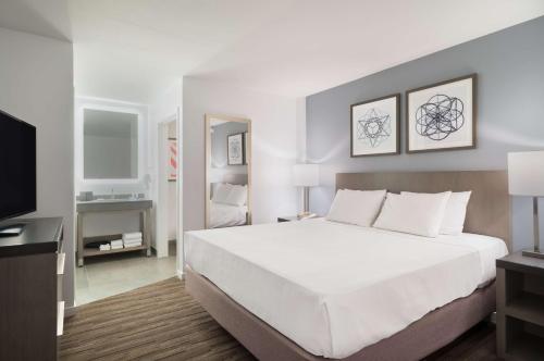 - une chambre avec un grand lit blanc et une télévision dans l'établissement Hyatt House White Plains, à White Plains