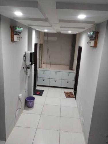 a bathroom with a white tiled floor and white cabinets at Park facing flat for yr comfort in Indore