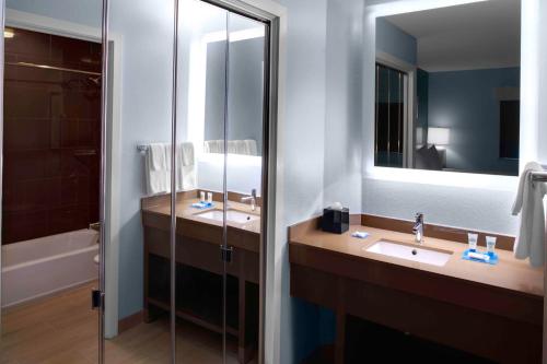 uma casa de banho com 2 lavatórios, um chuveiro e um espelho. em Hyatt House Morristown em Morristown