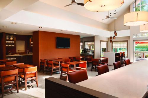 プレザントンにあるHyatt House Pleasantonのテーブルと椅子、薄型テレビ付きのレストランを提供しています。
