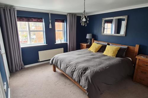 a bedroom with blue walls and a bed with yellow pillows at Four bed detached home in Nottingham in Nottingham