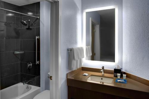 a bathroom with a sink and a tub and a mirror at Hyatt House Fishkill-Poughkeepsie in Fishkill