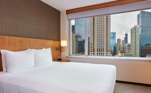 a bed in a hotel room with a large window at Hyatt Place Chicago River North in Chicago