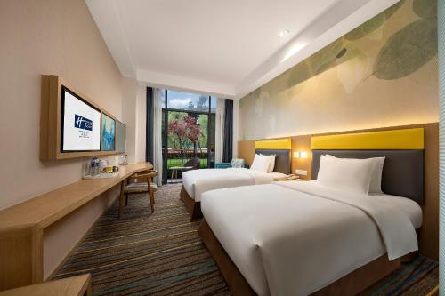 a hotel room with two beds and a television at Holiday Inn Express Emei Mountain by IHG in Emeishan