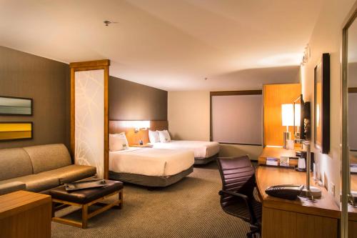 une chambre d'hôtel avec deux lits et un canapé dans l'établissement Hyatt Place Charlottesville, à Charlottesville