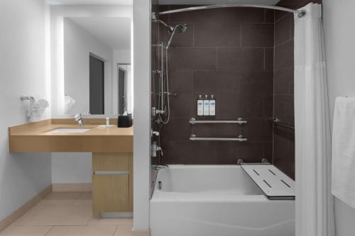 a bathroom with a shower and a tub and a sink at Hyatt House Raleigh North Hills in Raleigh