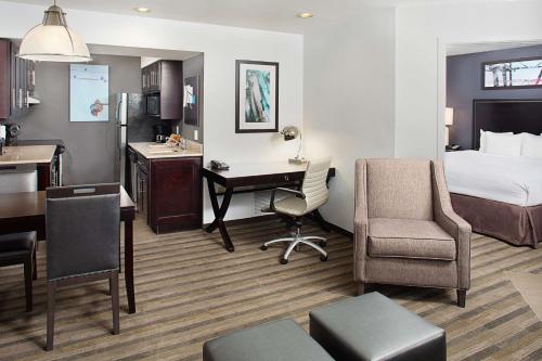 Hyatt House Belmont Redwood Shores في بلمونت: غرفه فندقيه بسرير ومكتب ومطبخ