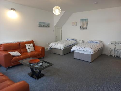 a living room with three beds and a couch at Sea Breeze Studio @ The Coach House in Saint Annes on the Sea