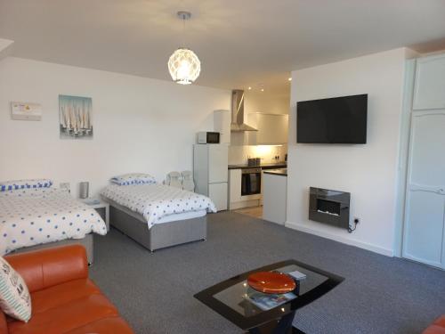 a living room with two beds and a tv at Sea Breeze Studio @ The Coach House in Saint Annes on the Sea