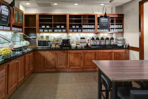 a kitchen with wooden cabinets and a bar with a table at Hyatt Place Boise/Towne Square in Boise