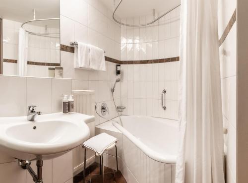 Hotel Löwen في لينغيناو: حمام أبيض مع حوض وحوض استحمام