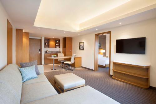 um quarto de hotel com um sofá, uma televisão e uma secretária em Hyatt Place Hyderabad Banjara Hills em Hyderabad