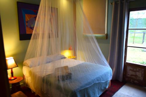 1 dormitorio con 1 cama con mosquitera en Little House in the Nursery grounded and welcoming, en Wallabadah
