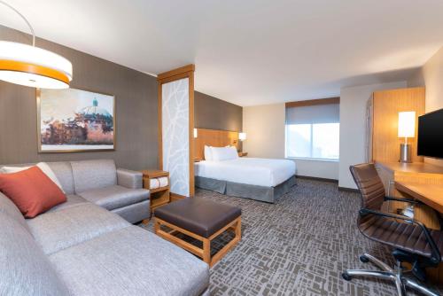 a hotel room with a couch and a bed at Hyatt Place Detroit/Royal Oak in Royal Oak