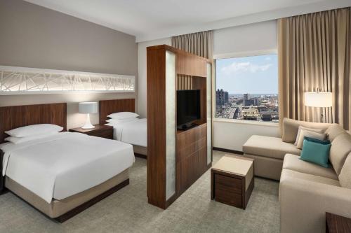 pokój hotelowy z łóżkiem, kanapą i telewizorem w obiekcie Hyatt House Jeddah Sari Street w mieście Dżudda