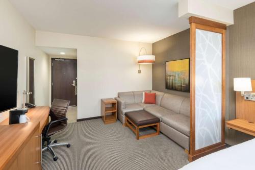 a hotel room with a couch and a desk at Hyatt Place Greenville Downtown in Greenville