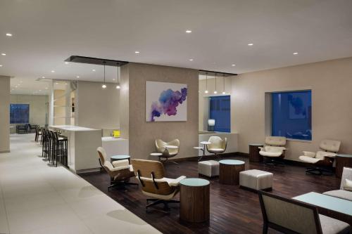 a lobby with a waiting area with tables and chairs at Hyatt House Jeddah Sari Street in Jeddah