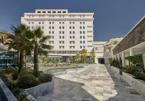 a large white building with palm trees in a courtyard at Hyatt Regency Addis Ababa in Addis Ababa
