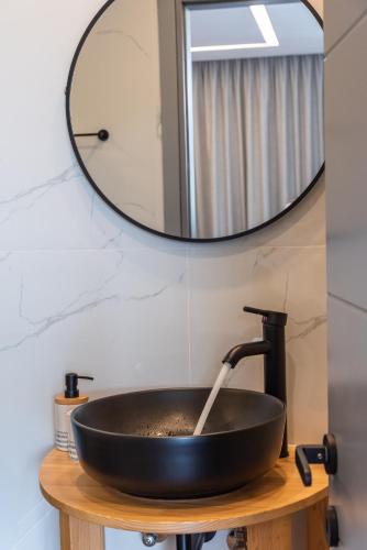 a black sink with a faucet and a mirror at Remvi apartments in Agios Nikolaos