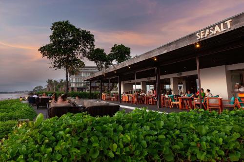a restaurant with people sitting at tables outside of it at Alila Seminyak in Seminyak