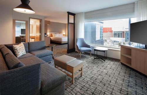 a living room with a couch and a room with a bed at Hyatt Place Moncton-Downtown in Moncton