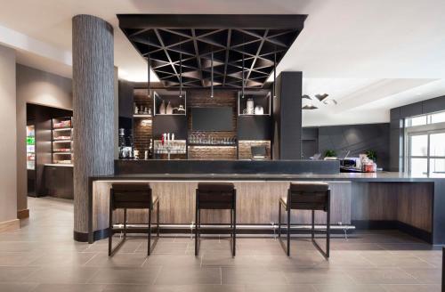 a bar in a restaurant with three stools at Hyatt Place Moncton-Downtown in Moncton