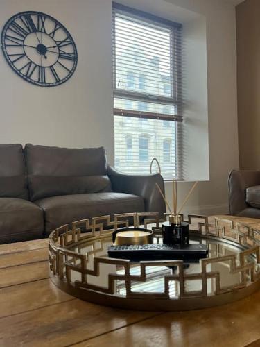 a living room with a coffee table and a clock at Tynwald Apartments in Douglas