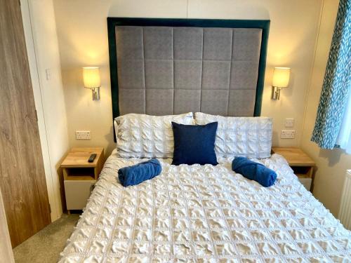 a bedroom with a large bed with blue pillows at 102, Duckpool Lodge in Bude
