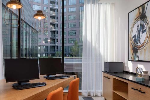 an office with two computer monitors on a desk with a large window at Hyatt Place Boston/Seaport District in Boston