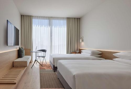 a hotel room with three beds and a television at Hyatt Centric Melbourne in Melbourne