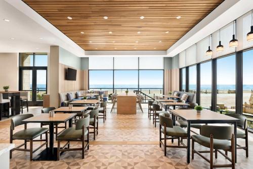 ein Restaurant mit Tischen und Stühlen und großen Fenstern in der Unterkunft Hyatt Place Virginia Beach Oceanfront in Virginia Beach