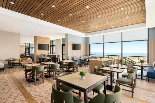 um restaurante com mesas e cadeiras e vista para o oceano em Hyatt Place Virginia Beach Oceanfront em Virginia Beach