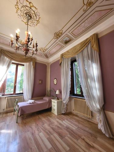 um quarto com uma cama, janelas e um lustre em Villa Bartolini Bevagna em Bevagna