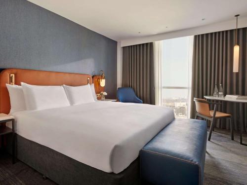 um quarto de hotel com uma grande cama branca e uma secretária em Hyatt Regency London Stratford em Londres