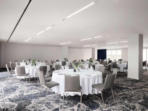 a large room with white tables and chairs and a room with tables and chairsktop at Hyatt Regency London Stratford in London