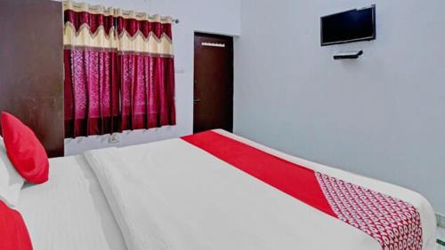 a bedroom with a white and red bed and a television at Backpackers Dinesh Home Stay in Khajurāho