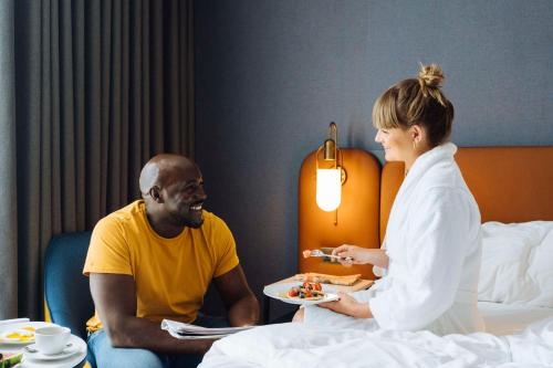 a woman giving a man a plate of food at Hyatt Regency London Stratford in London
