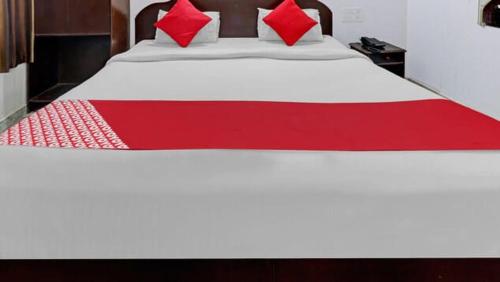 a large white bed with red pillows on it at Backpackers Dinesh Home Stay in Khajurāho