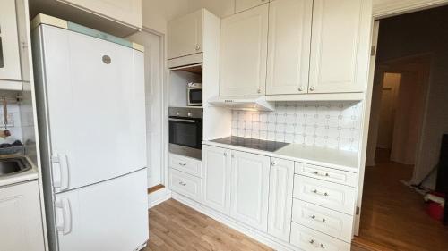 a white kitchen with white cabinets and a refrigerator at Oslo-Frogner in Oslo
