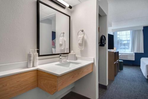 a bathroom with a sink and a large mirror at Spark By Hilton Rochester University Area in Rochester