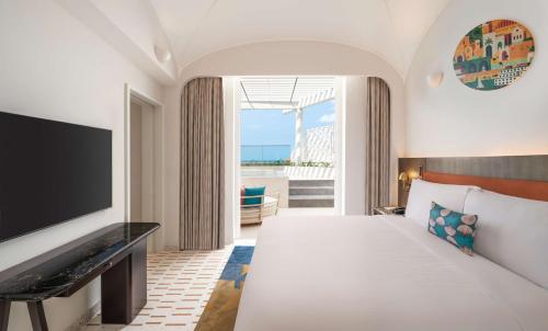 um quarto de hotel com uma cama e uma televisão em La Festa Phu Quoc, Curio Collection By Hilton em Duong Dong